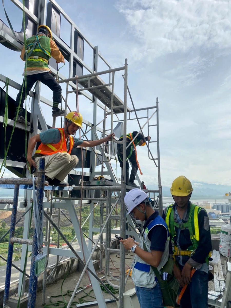 Hệ khung thép và nhân sự làm việc tại vị trí lắp biển trên cao